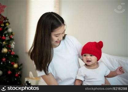 Mother and newborn baby wearing red hats In the white bedroom, warm sunlight in the evening of the day. Prepare to celebrate Christmas
