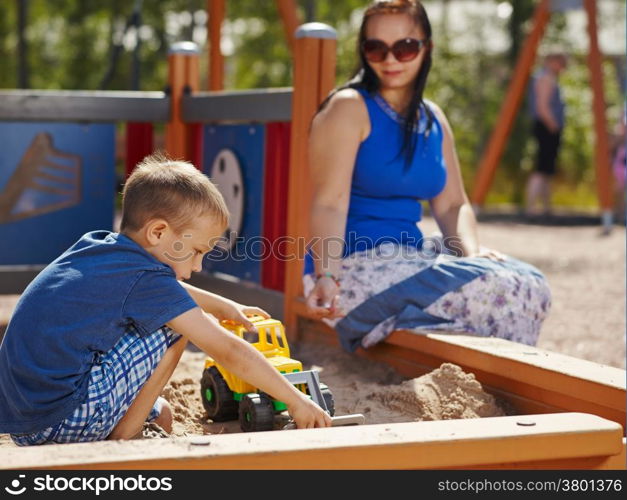 Mother and six year old boy child play together in sandbox