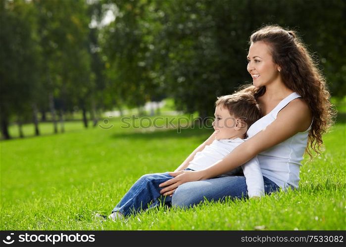 Mother and small son sit on a summer garden lawn