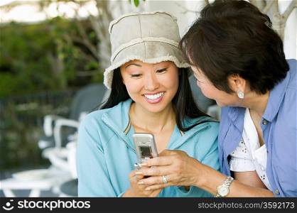 Mother and Smiling Daughter Using Cell Phone