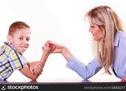 Mother and son arm wrestle sit at table.. Spending time with family fun and family bonds. Mother and son arm wrestle and have fun indoors.