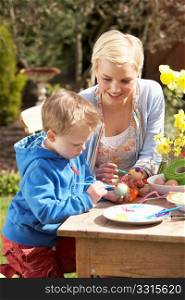 Mother And Son Decorating Easter Eggs On Table Outdoors