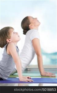 Mother and son doing yoga exercise at home - focus on son
