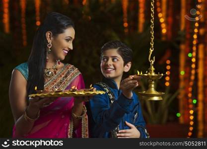 Mother and son holding diyas