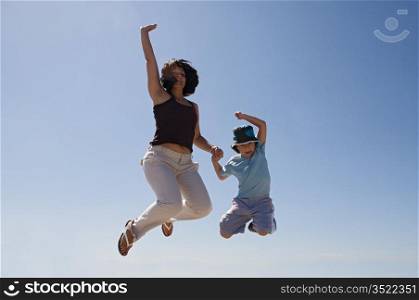 Mother and son jumping a over sky background