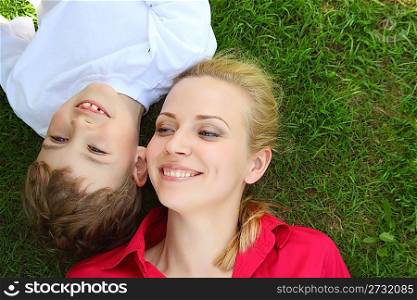 Mother and son lie head to head on grass