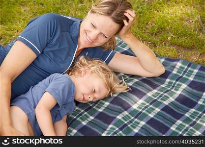 Mother and son lying on picnic blanket