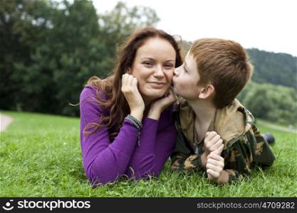 Mother and son lying on the green grass in the park