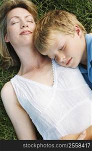 Mother and son lying outdoors sleeping