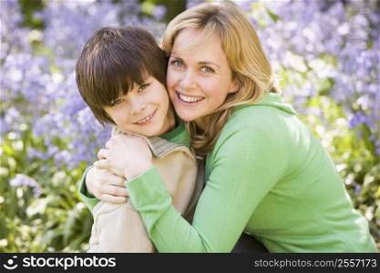 Mother and son outdoors embracing and smiling