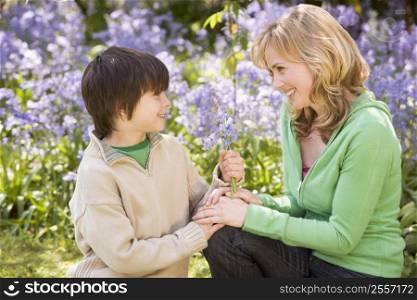 Mother and son outdoors holding flowers smiling