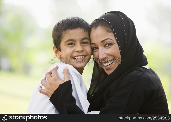 Mother and son outdoors in park embracing and smiling (selective focus)