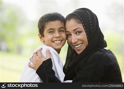 Mother and son outdoors in park embracing and smiling (selective focus)