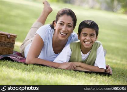 Mother and son outdoors in park with picnic smiling (selective focus)