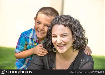 Mother and son outside in garden. both are happy, and smiling while son gives mother a hug.