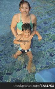 mother and son playing with happiness in water pool