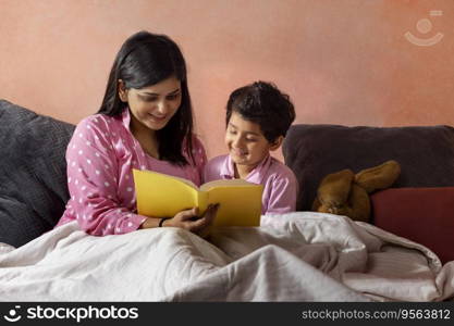 Mother and son reading a book on bed