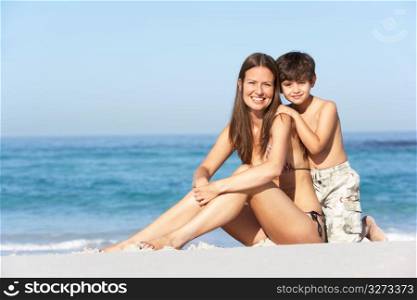 Mother And Son Relaxing Together On Beach Holiday