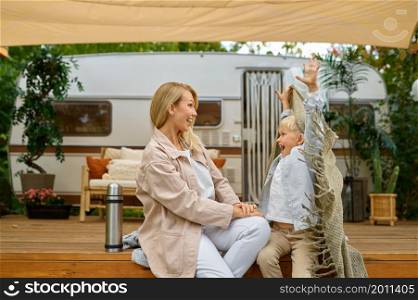Mother and son resting in the trailer, summer camping. Parents with children travel in camp car, nature and forest on background. Campsite adventure, travelling lifestyle. Mother and son resting in trailer, summer camping