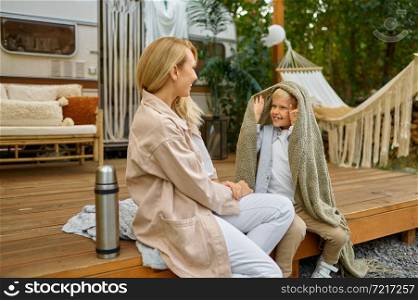 Mother and son resting in the trailer, summer camping. Parents with children travel in camp car, nature and forest on background. Campsite adventure, travelling lifestyle. Mother and son resting in trailer, summer camping