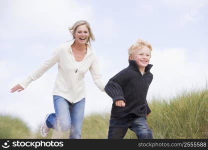 Mother and son running on beach smiling