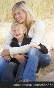 Mother and son sitting on beach smiling