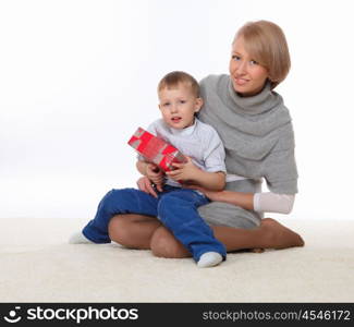 mother and son sitting on the floor and holding a present box