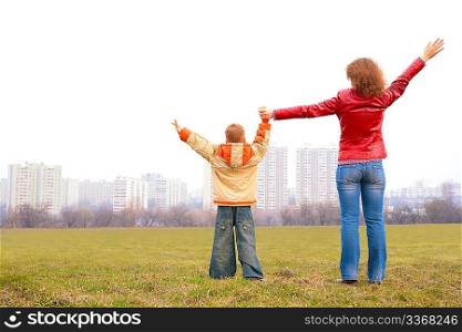 mother and son stand outdoor with lifted hands
