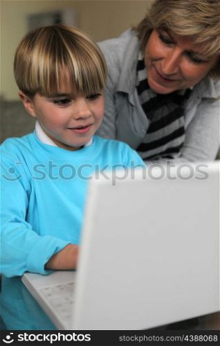 Mother and son using laptop together on sofa