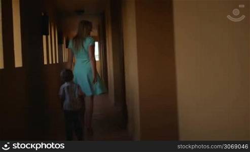 Mother and son walking along the hotel hall. Boy running away from his mom