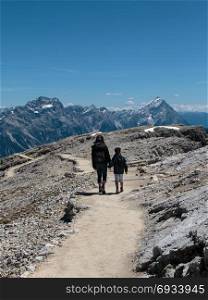 Mother and Son Walking in Stone Path among Barren Mountains in Italian Dolomites Alps in Summer Time