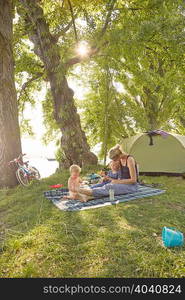 Mother and sons relaxing on picnic blanket in rural setting