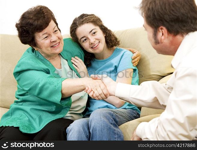 Mother and teen girl shake hands with a counselor.