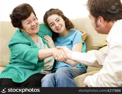 Mother and teen girl shake hands with a counselor.