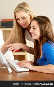 Mother And Teenage Daughter At Home Using Computer