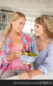 Mother and teenage daughter enjoying food at home