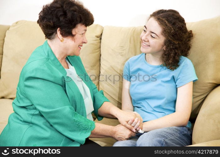 Mother and teenage daughter having a conversation together on the couch.