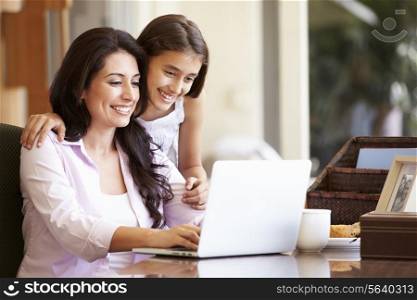 Mother And Teenage Daughter Looking At Laptop Together