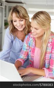 Mother and teenage daughter using laptop