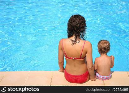 Mother and the daughter sit at pool