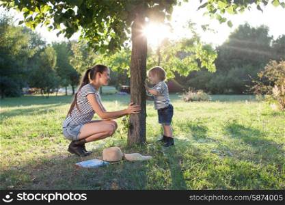 Mother and toddler playing the hide-and-seek outdoors