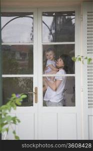 Mother and toddler standing inside a door with glass windows