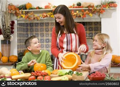 Mother and two children carving jack o lanterns on Halloween and smiling