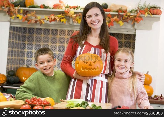 Mother and two children carving jack o lanterns on Halloween and smiling