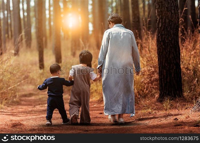 mother and two children walking in pine wood