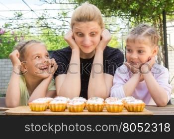 Mother and two daughters having fun and looking at easter cupcakes