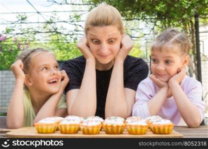 Mother and two daughters having fun and looking at easter cupcakes