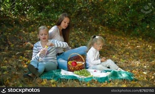 Mother and two daughters having picnic in the autumn park