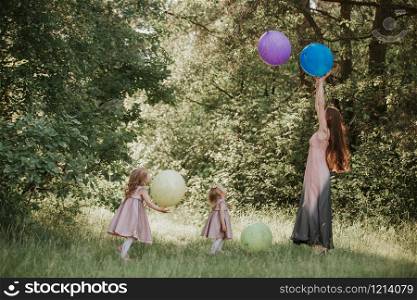 Mother and two daughters holding hands circling. Family time together. Girls with balloons. Soft focus. Funny time. Mother and two daughters holding hands circling. Family time together. Funny time. Girls with balloons. Soft focus