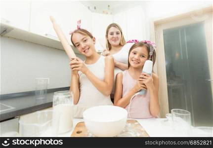 Mother and two daughters posing on kitchen while cooking